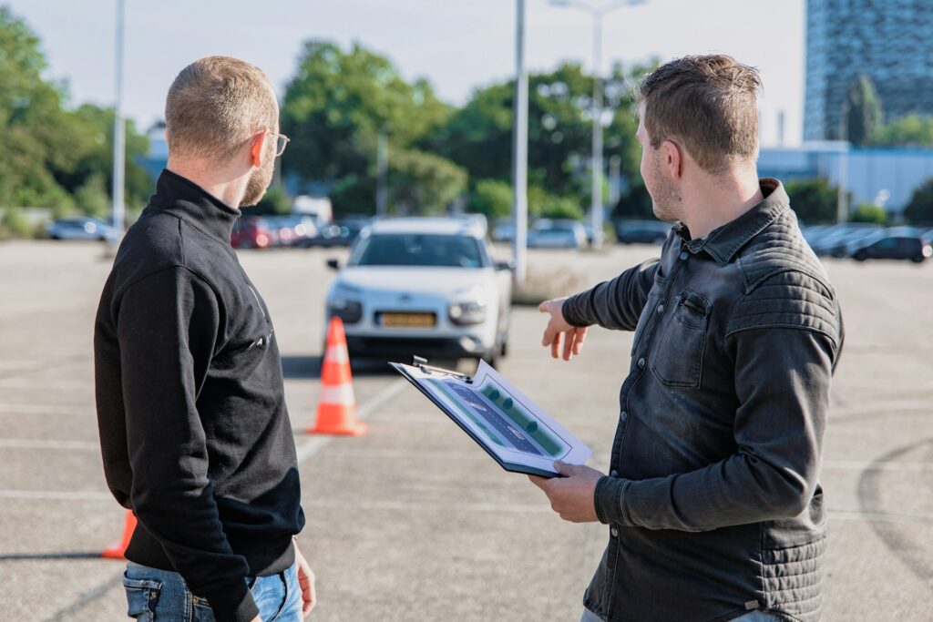 Lernen die Fahrschüler aus Ihren Fehlern? Ein Fahrlehrer und Fahrschüler unterhalten sich auf dem Prüfungsgelände des TÜV. Dort starten die meisten praktischen Fahrprüfungen. 